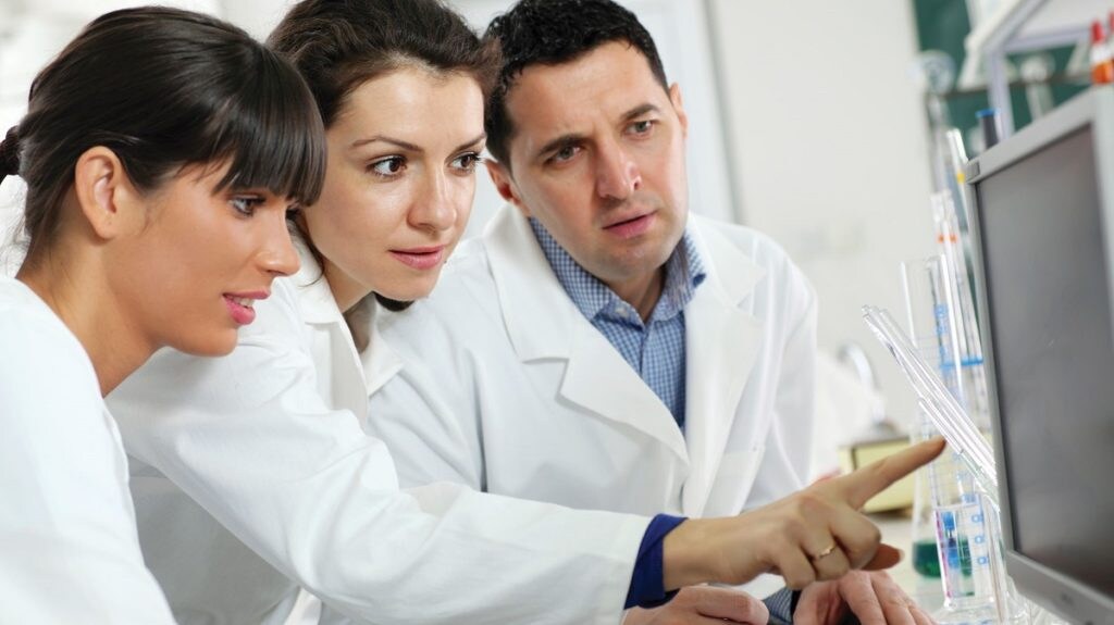 Doctors working together in lab looking at computer display.