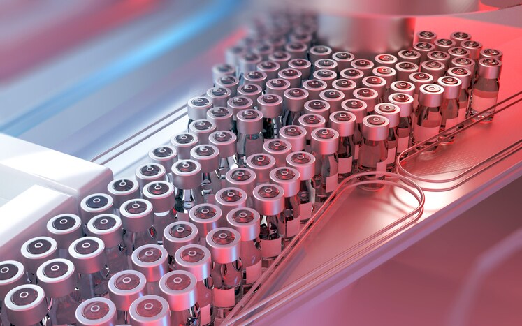 Vaccine doses in glass vials with metal caps and blank labels being produced in an automated pharmaceutical industry with conveyor belts. Industrial background, production line, manufacturing equipment, medicine and vaccinations. Digitally generated image. Selective focus.
