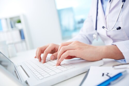 Close-up of hands of a nurse typing on laptop. Image: Kaspars Grinvalds/Shutterstock.com.