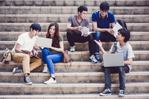 Group of teenagers sitting on stairs and talking. Image: Nonwarit/Shutterstock.com