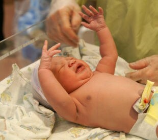 A newborn African-American girl crying on an examination table. Image: Damon Yancy/Shutterstock.com.