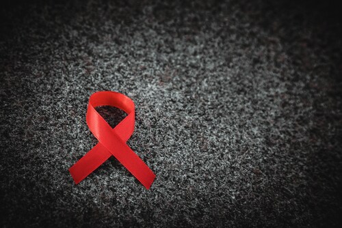 Red ribbon on granite, black and white, World AIDS Day concept. Image: Alexxndr/Shutterstock.com.