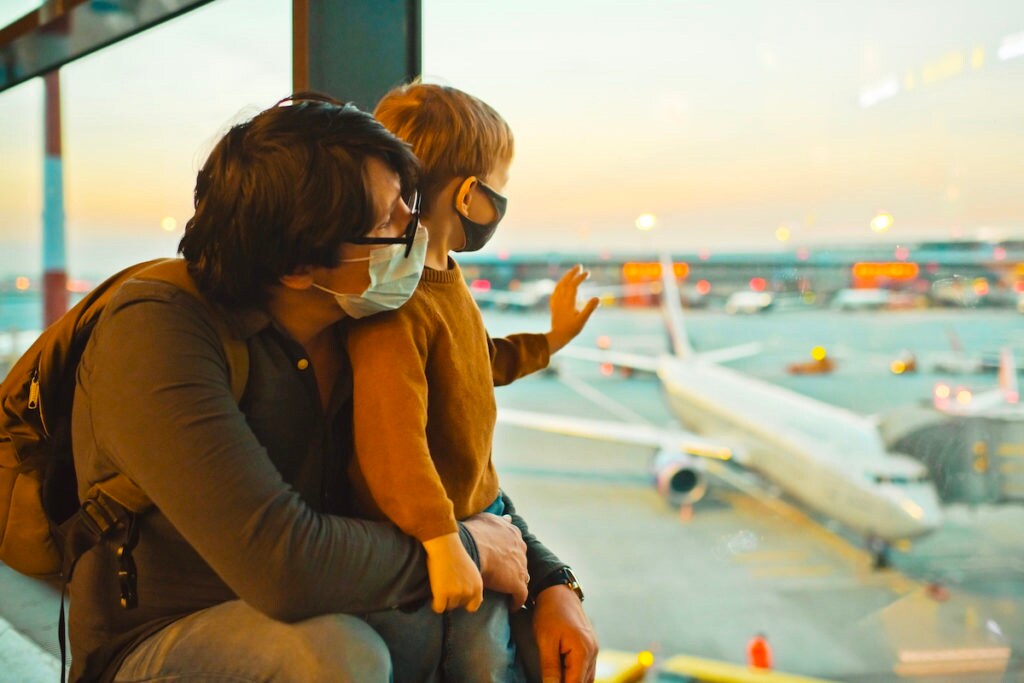 Father and son at an airport wearing masks