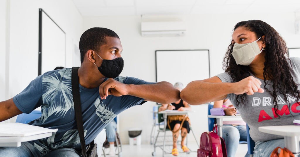 Two people bumping elbows with masks on