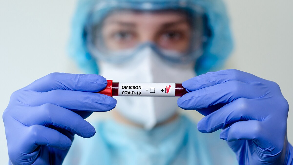 Scientist with blue gloves holding an Omicron vial