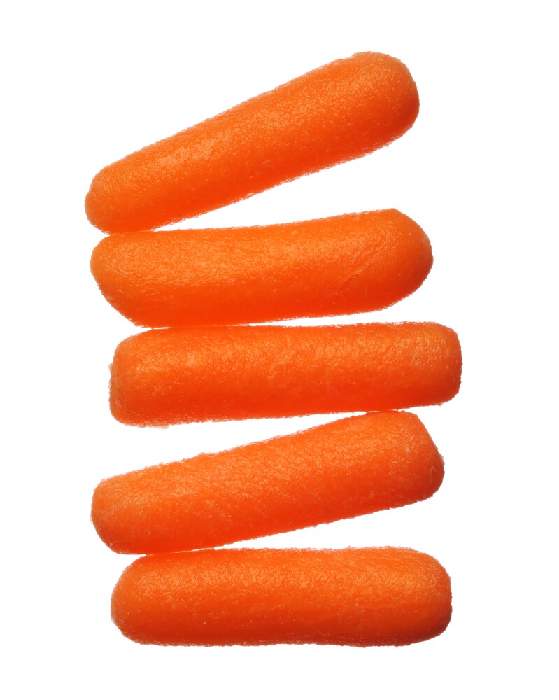 Five baby carrots lined up, isolated on a white background