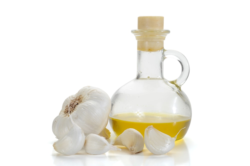 Garlic oil, isolated on a white background with fresh cloves of garlic
