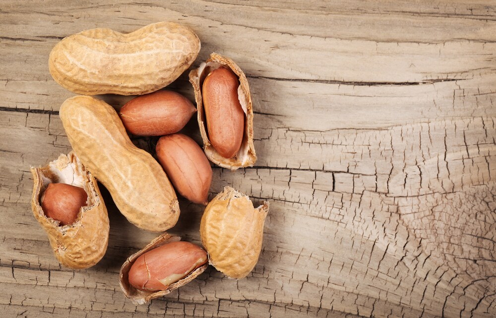 Shelled peanuts and peanuts in shells on wood surface