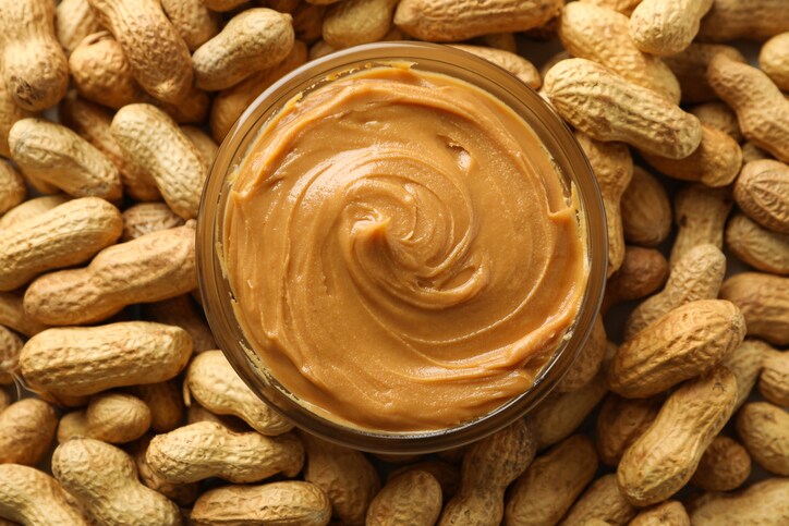Jar with peanut butter on peanut background, close up