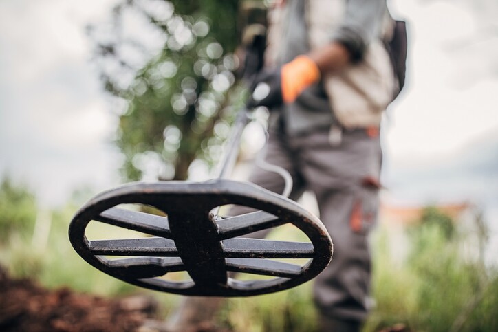 image of person using metal detector to find gold