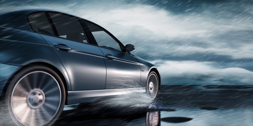 Black Luxury Car driving through heavy Rain on empty Road