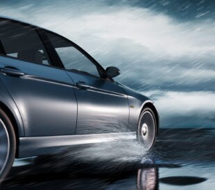 Black Luxury Car driving through heavy Rain on empty Road