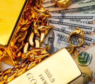 Jewelry buyer, pawn shop and buy and sell precious metals concept theme with a pile of cash in US dollars, golden rings, necklace bracelet and gold bullion isolated on white background
