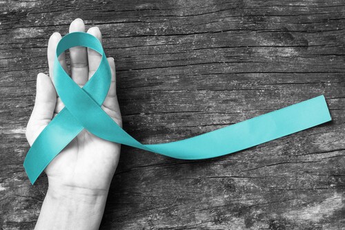 Teal ribbon awareness to support Ovarian Cancer PCOS on human hand with aging wood background: Symbolic concept for raising awareness/concerns/help and campaign on people living with illness. Image: Chinnapong/Shutterstock.com.