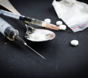 Drug syringe and cooked heroin on spoon. Image: FabrikaSimf/Shutterstock.com.