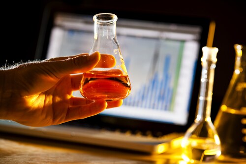 Scientist doing research and holding a beaker. Image: Brian Goodman/Shutterstock.com.