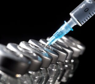 Glass medicine vials and syringe on black background. Image: Nikolay Litov/Shutterstock.com.