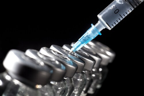 Glass medicine vials and syringe on black background. Image: Nikolay Litov/Shutterstock.com.