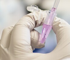 gloved scientists hand holding a microcentrifuge tube containing pink-colored liquid that is being withdrawn using a pipette gloved scientists hand holding a microcentrifuge tube containing pink-colored liquid that is being withdrawn using a pipette